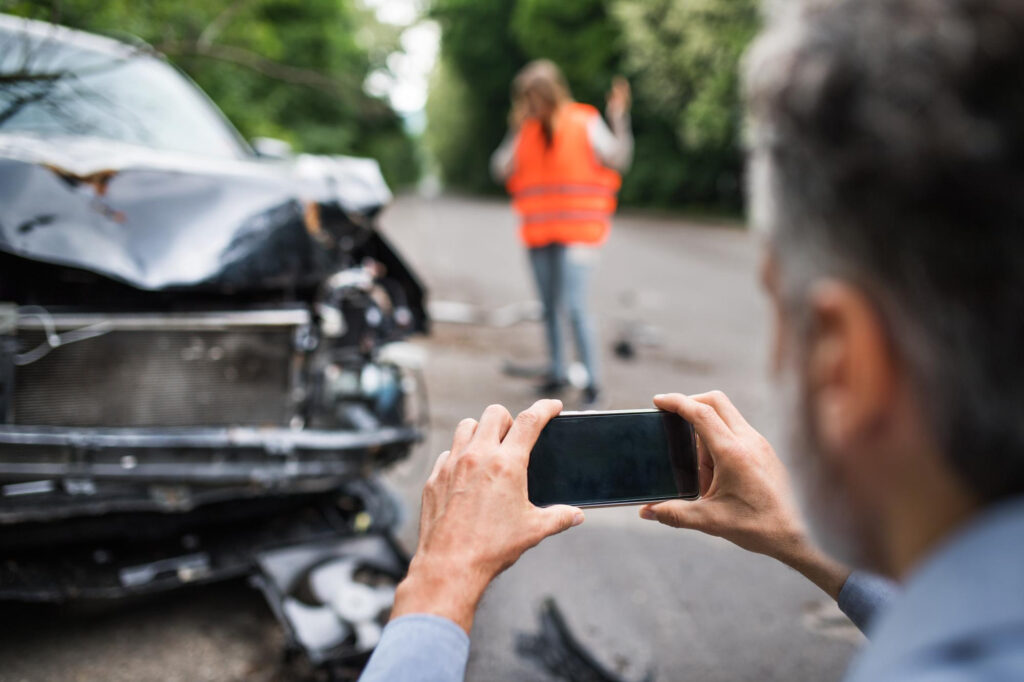 Homme prenant en photo sa voiture après un accident de la route